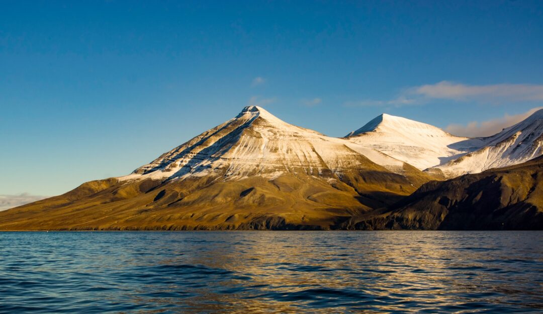Snow-capped mountains and ocean at Svalbard, Arctic wilderness landscape during summer expedition