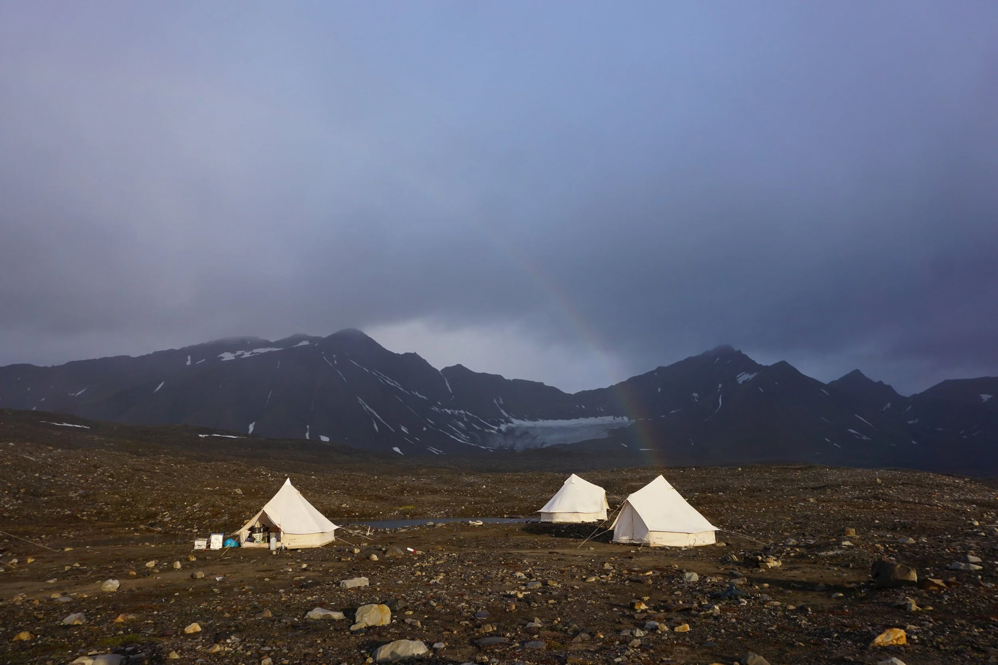Camping tents in Arctic wilderness with snow-capped mountains in Svalbard