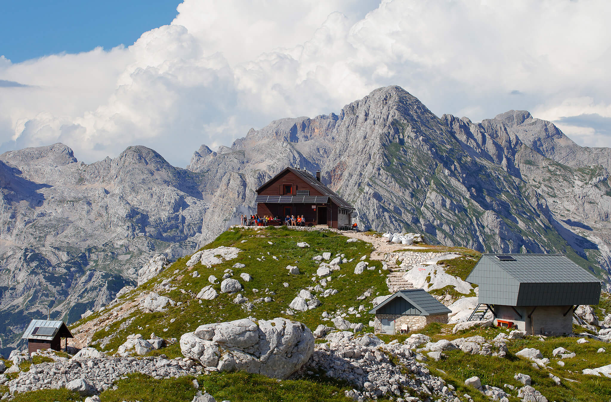 Mountain hiking huts on a grassy ridge in Slovenia’s Alps under rocky peaks