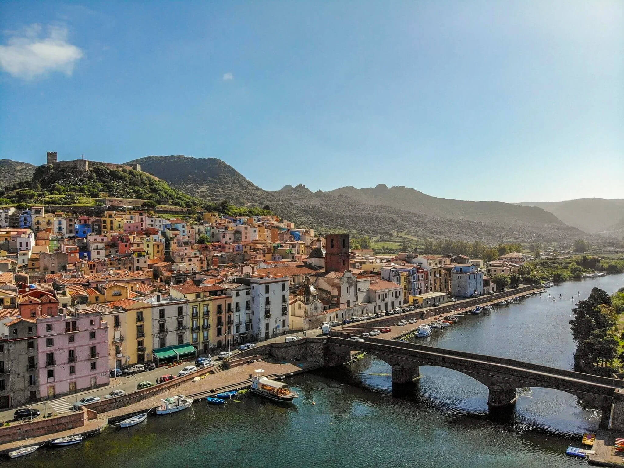 Colourful coastal town in Sardinia with harbour boats and a bridge over the river