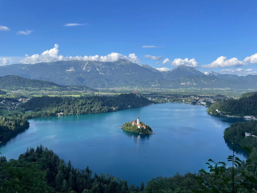 Serene lake in Slovenia with an island church and mountain views, ideal for hut-to-hut hiking