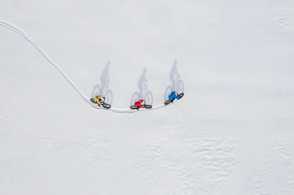 Cross-country skiers glide on fresh snow, with three skiers spaced out on a winter slope