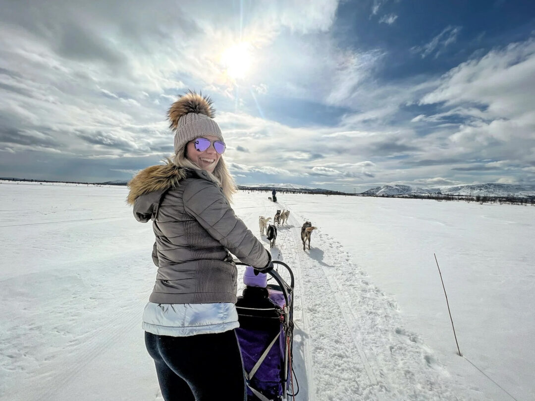 Woman ice-skiing across snowy landscape, Nordic winter scenery in Norway under blue sky