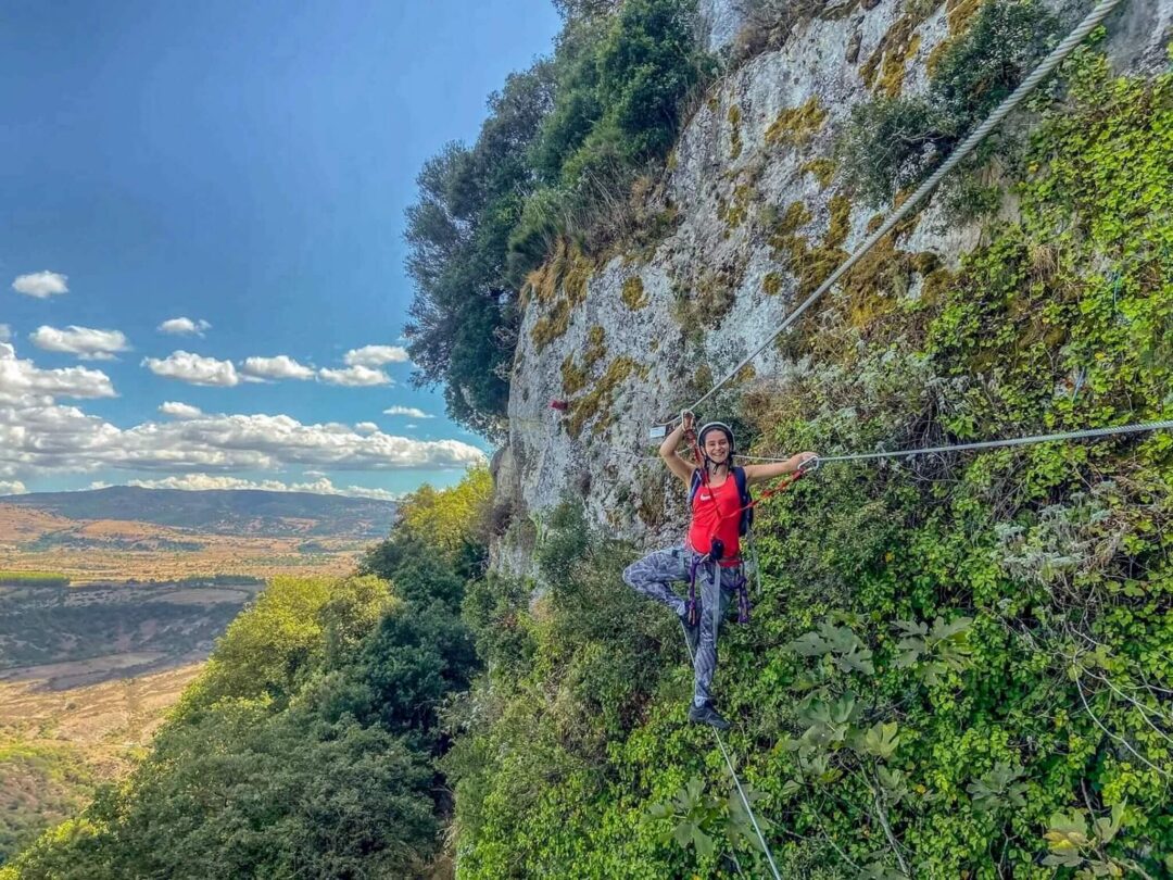 Woman walking along a cable on a rocky cliff during an outdoor adventure hike