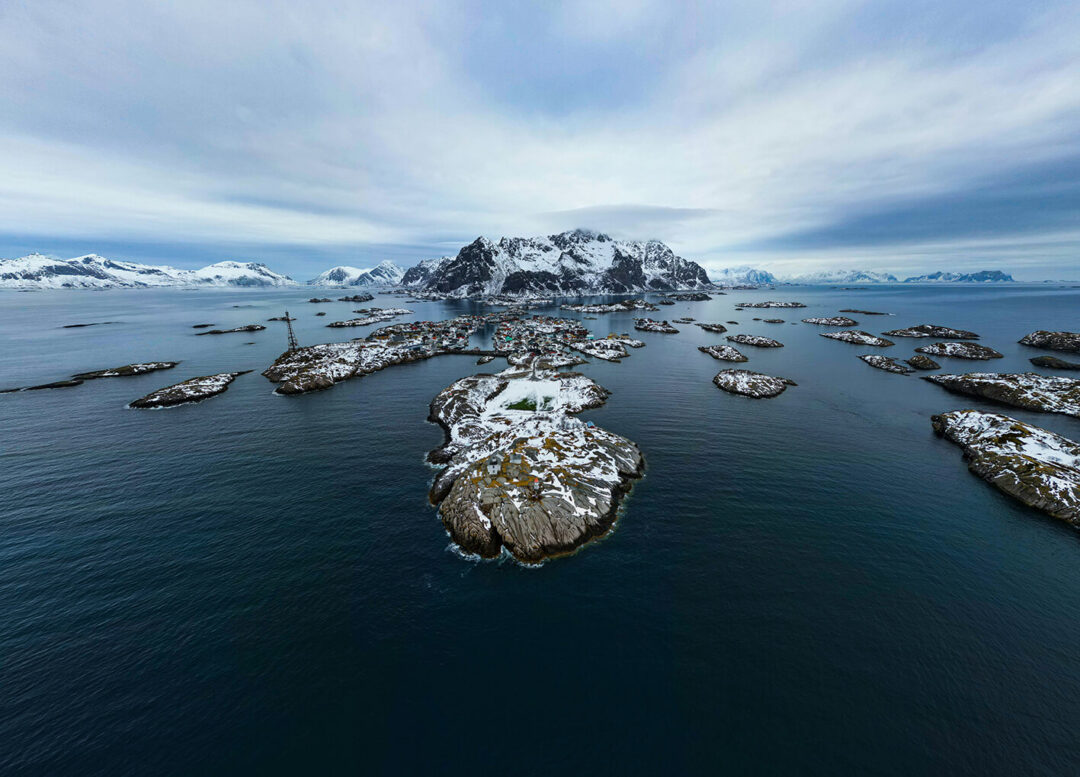 Aerial view of snowy islands and fjord water in Norway’s Lofoten with rocky islets and mountains