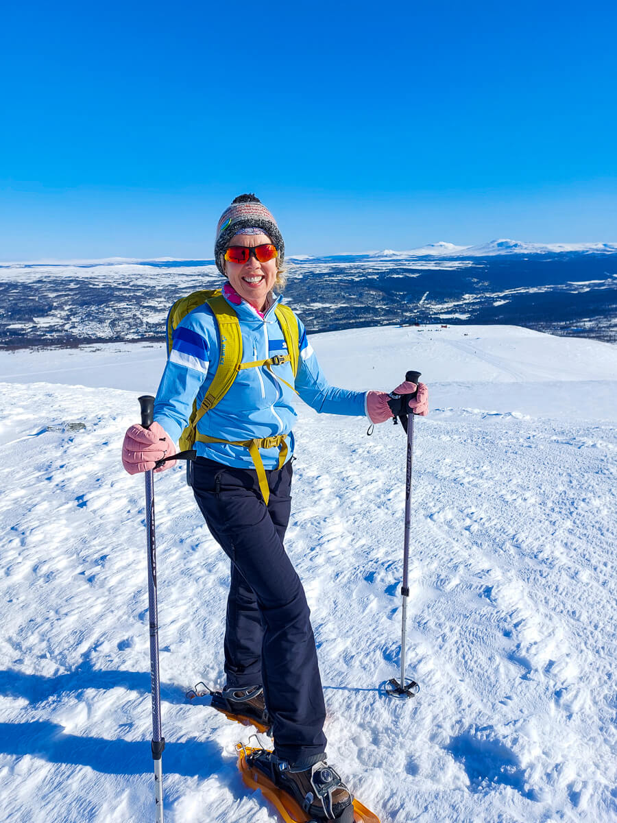 Woman cross-country skiing on a snowy mountain slope under a clear blue sky
