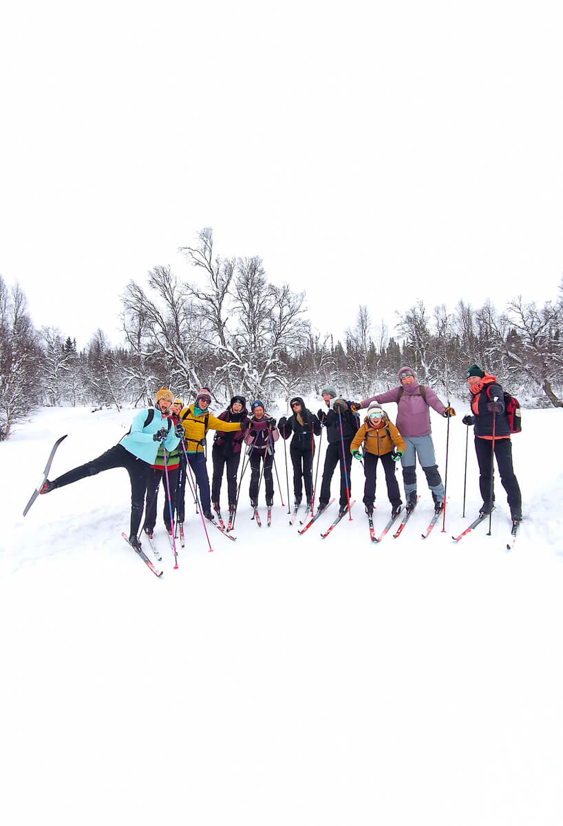 Women cross-country skiing together in a snowy winter landscape with trees in the background.