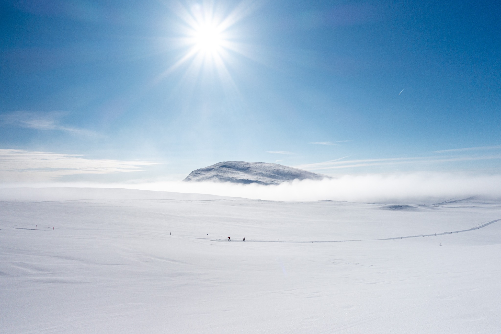 Snowy ski landscape with mist over distant hills under bright sun