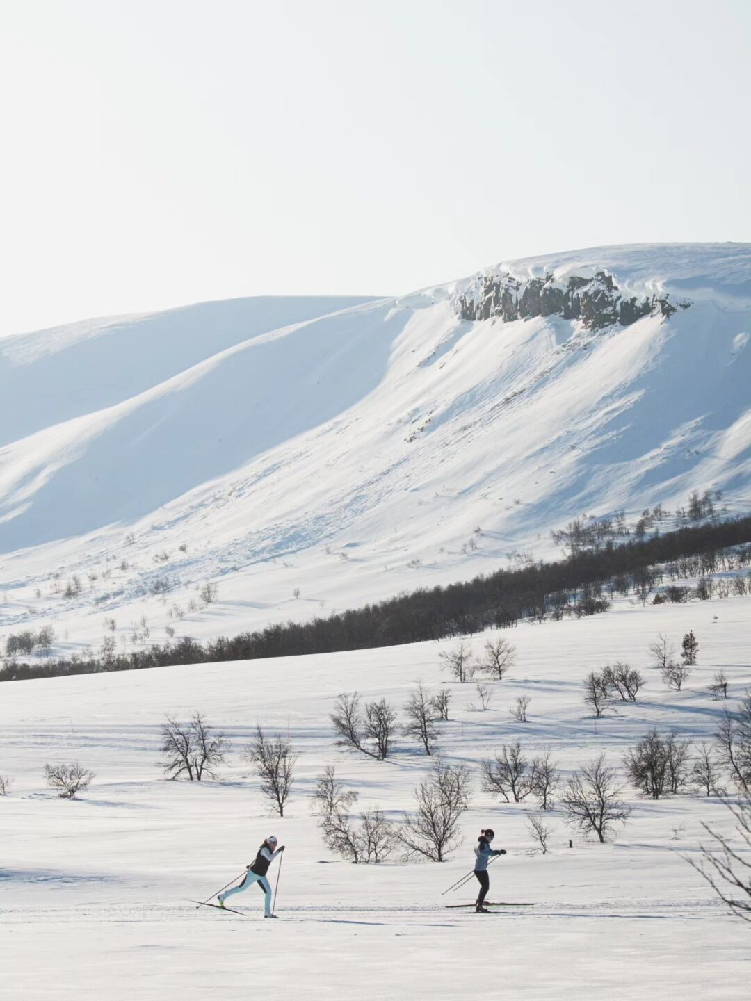 Women cross-country skiing on snowy hillsides in a winter mountain landscape