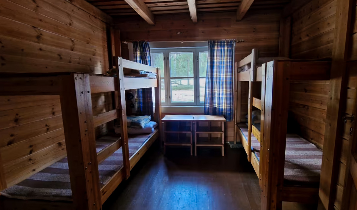 Wooden cabin interior with bunk beds and table, window view of snowy landscape in Finland