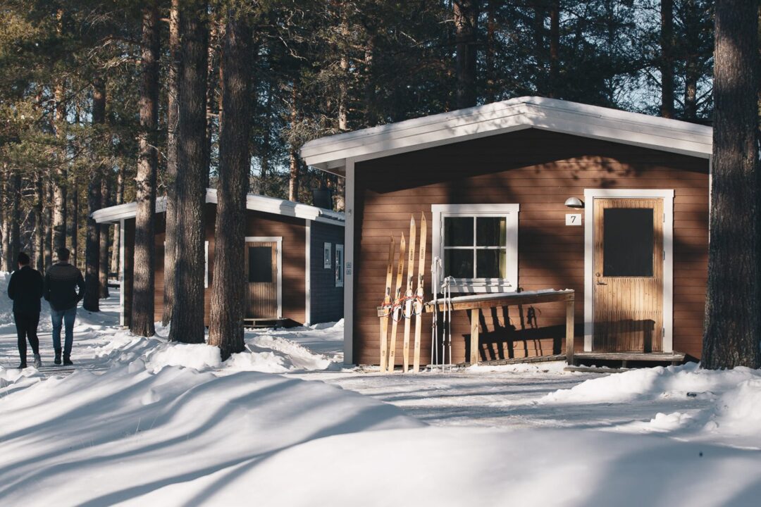 Snowy Lapland forest cabin with skis and poles outside, winter adventure setting