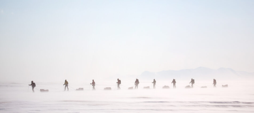 Women snowshoeing across a snowy Arctic plain in fog, Svalbard