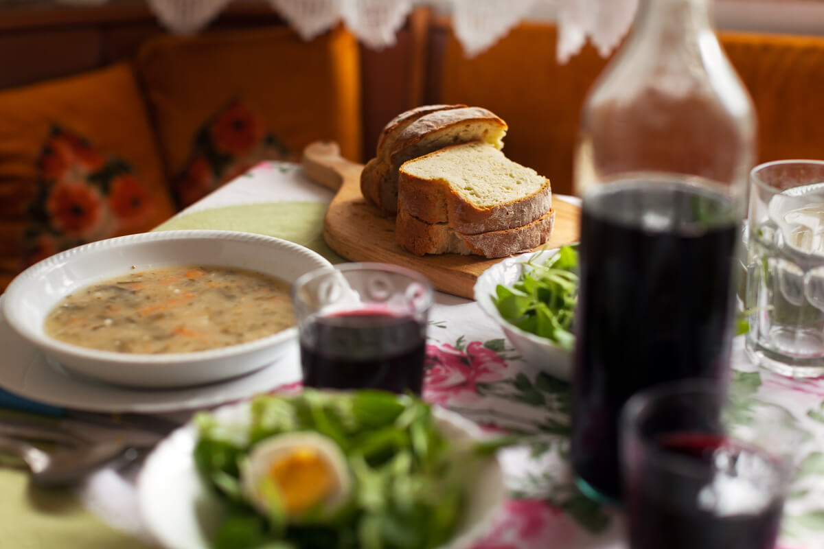 Rustic hut-style meal table with soup, bread, and drinks during a hiking adventure