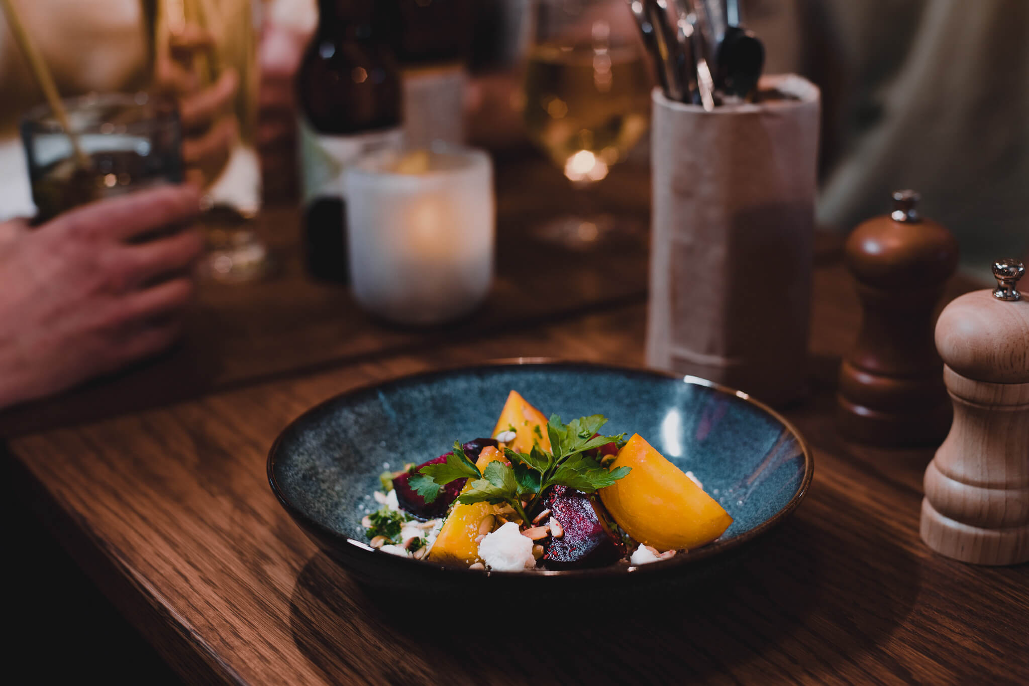 Dish of food on a restaurant table, with herbs and orange garnish in a blue bowl