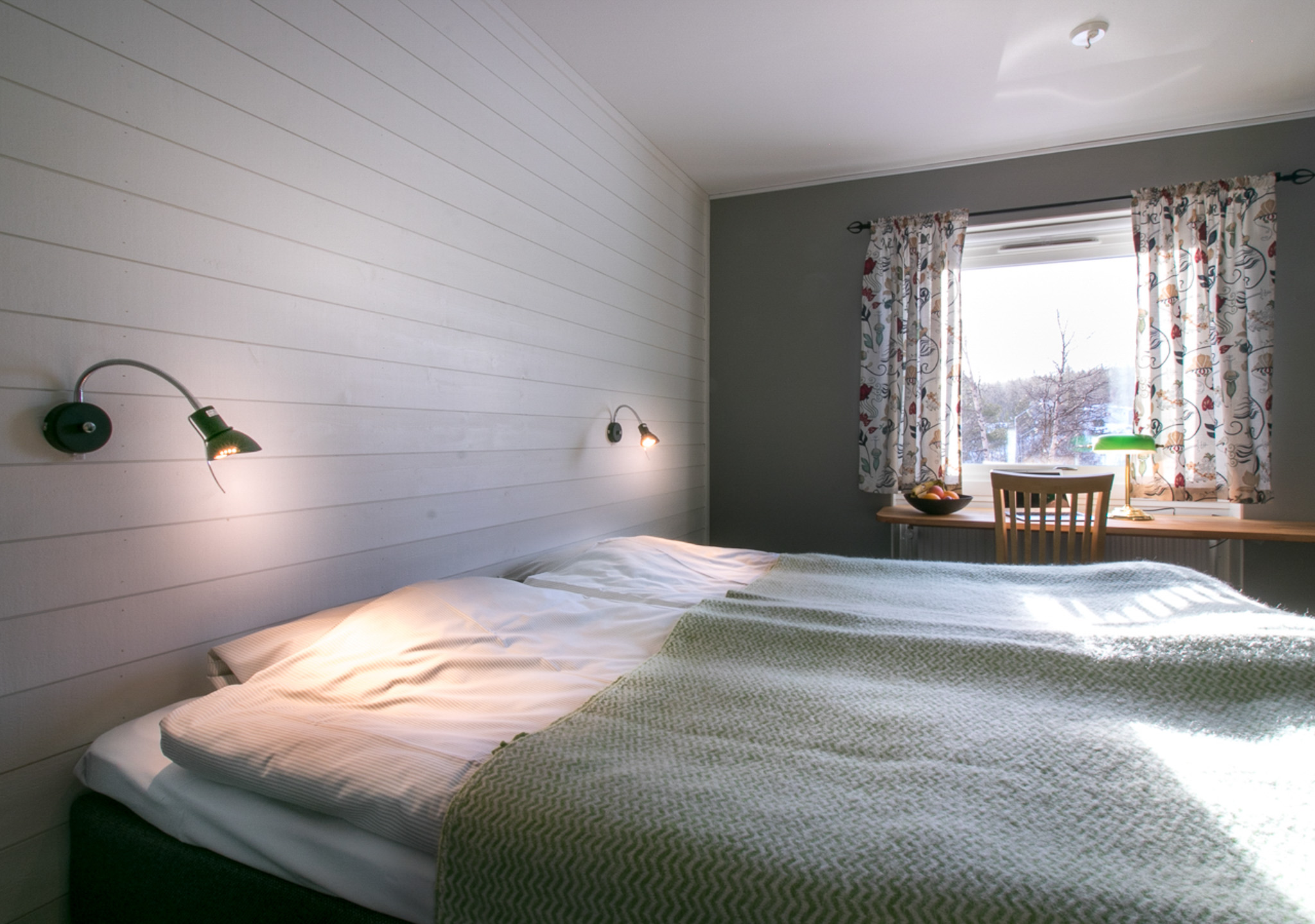 Cozy bedroom with a double bed and window showing winter trees in Sweden