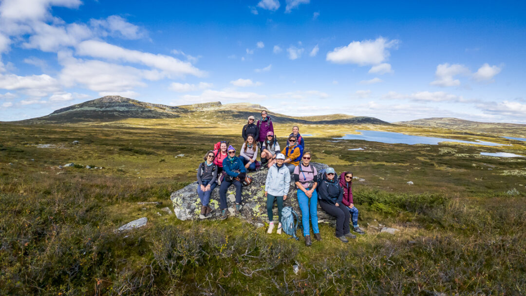 Group of women hiking with backpacks in Norwegian mountains under a blue sky