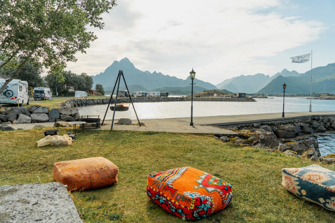 Lakeside campsite with colourful cushions on grass and mountains in the background