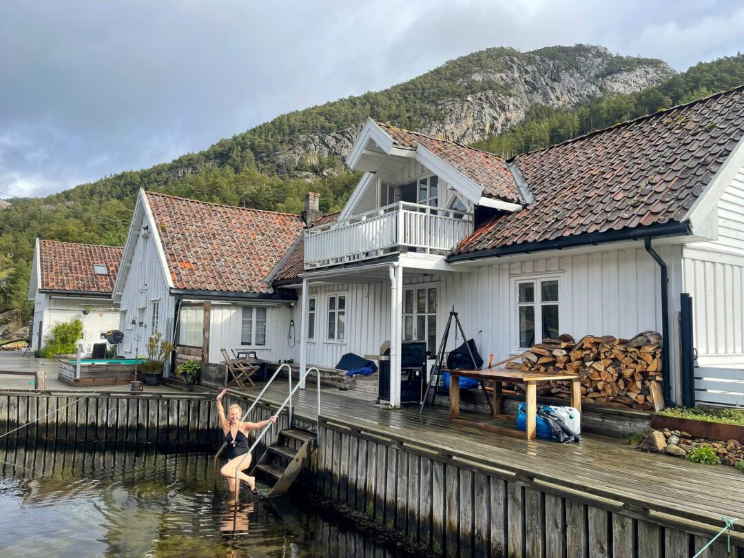 Woman holding a paddle at a quay beside a fjord house in Norway, kayaking diary setting
