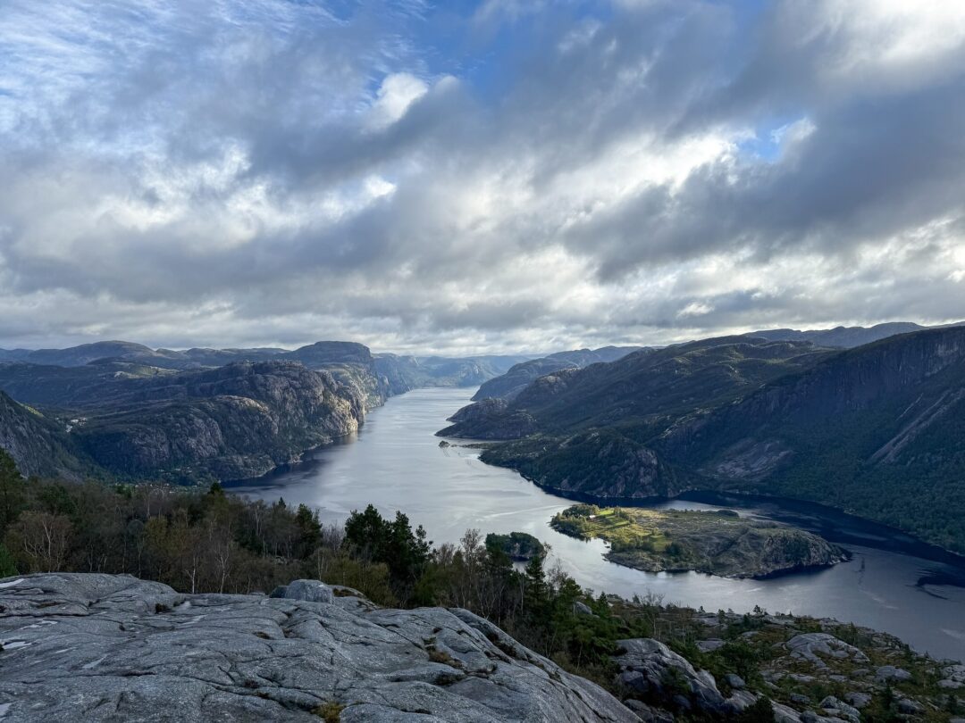 Norwegian fjord view from a rocky cliff with a winding river under a cloudy sky