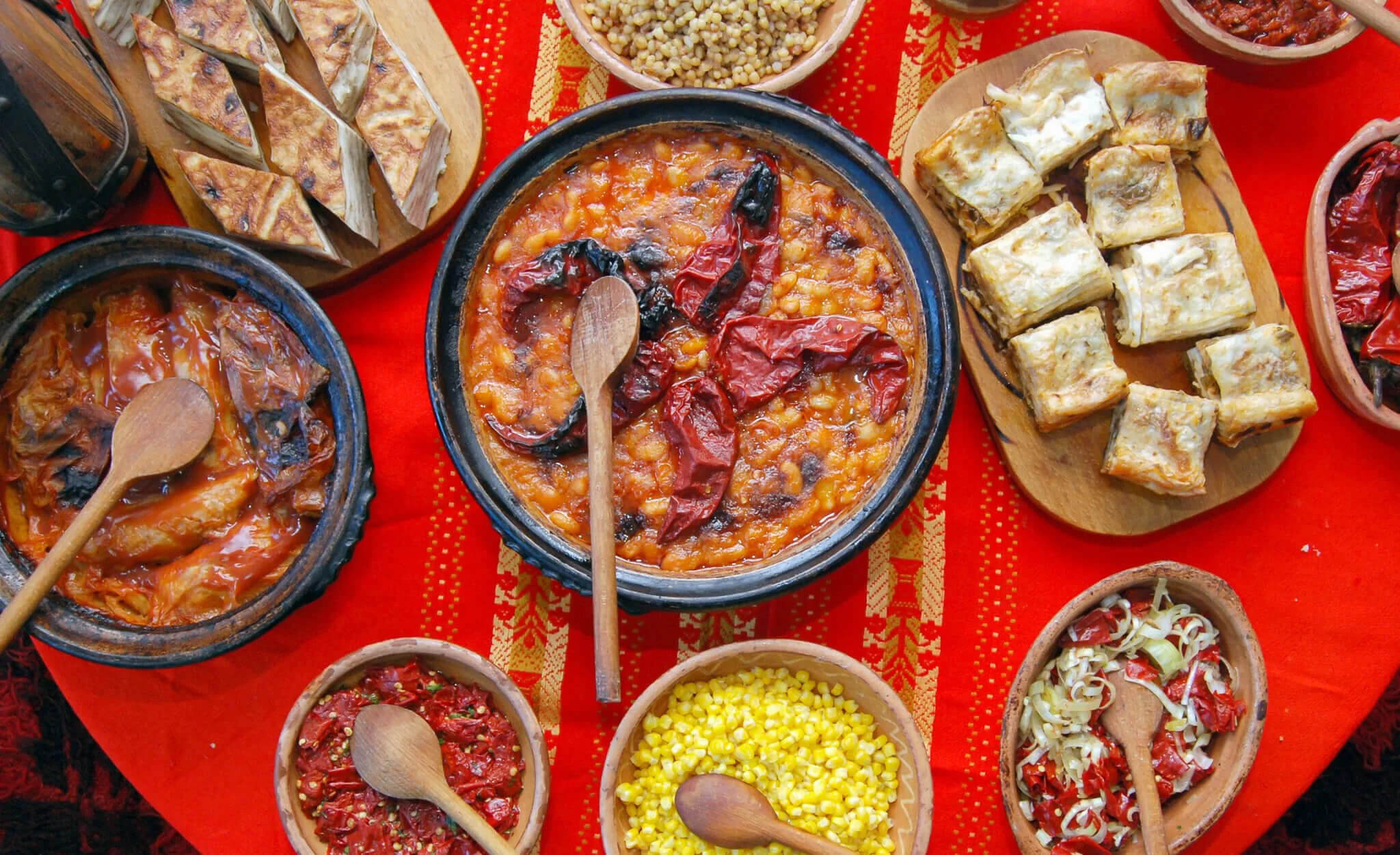 Women-only adventure food table with bowls of stew, beans and flatbread, outdoors in Europe