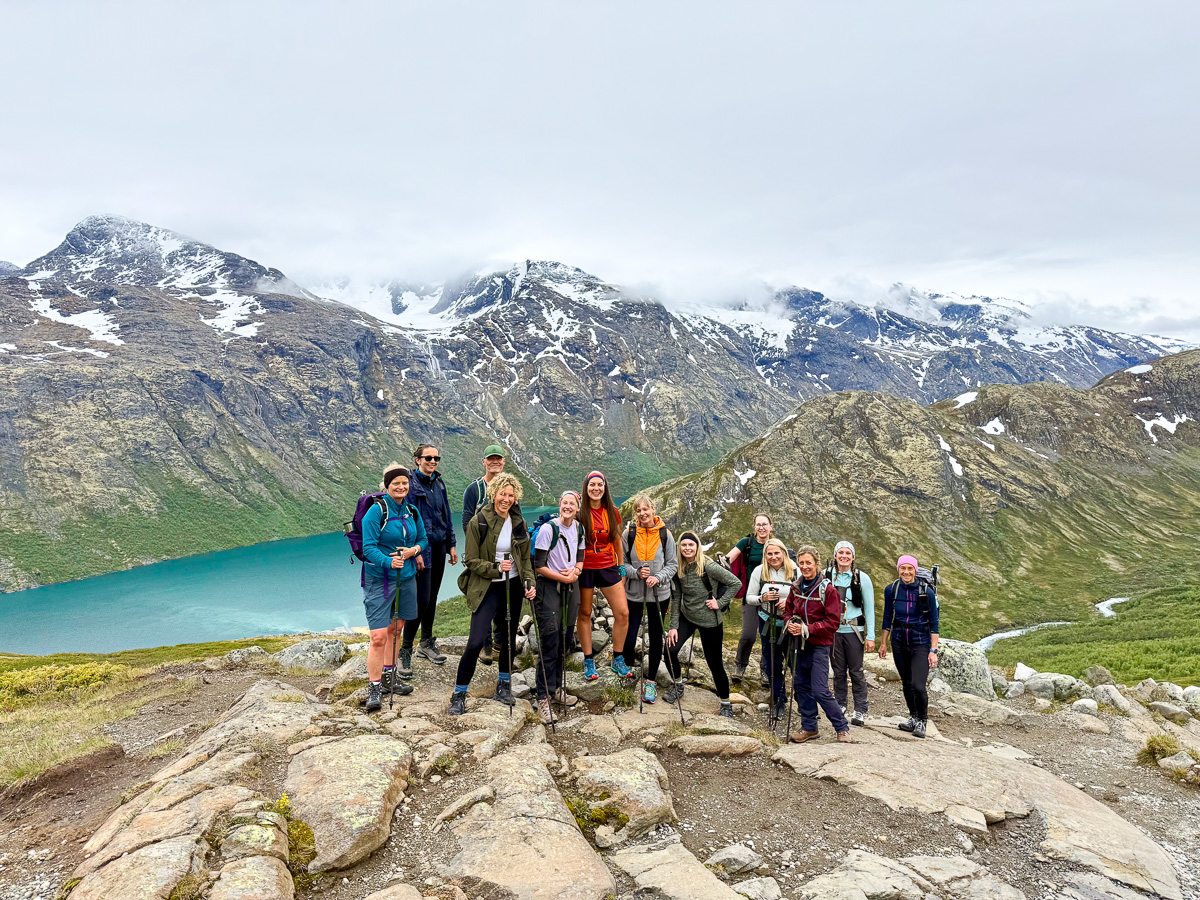Group of women hikers posing on a rocky overlook above a turquoise lake in Norway’s mountains