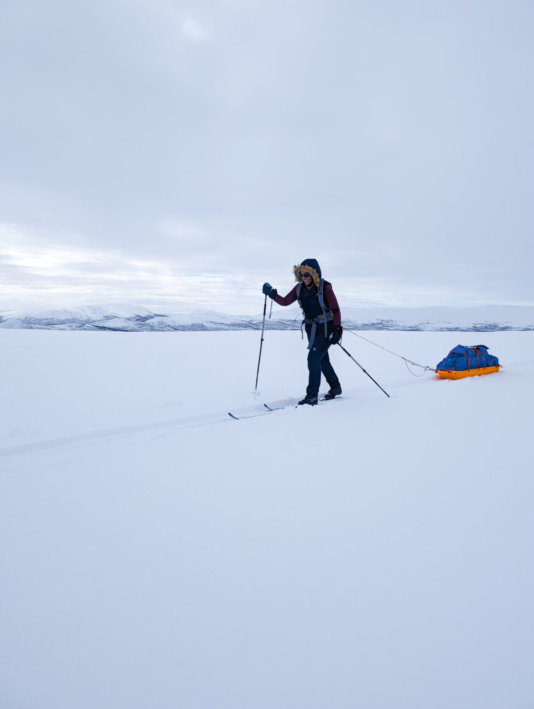 Skiing across the snow near the Arctic Circle, a woman with poles and a loaded rucksack on a winter route