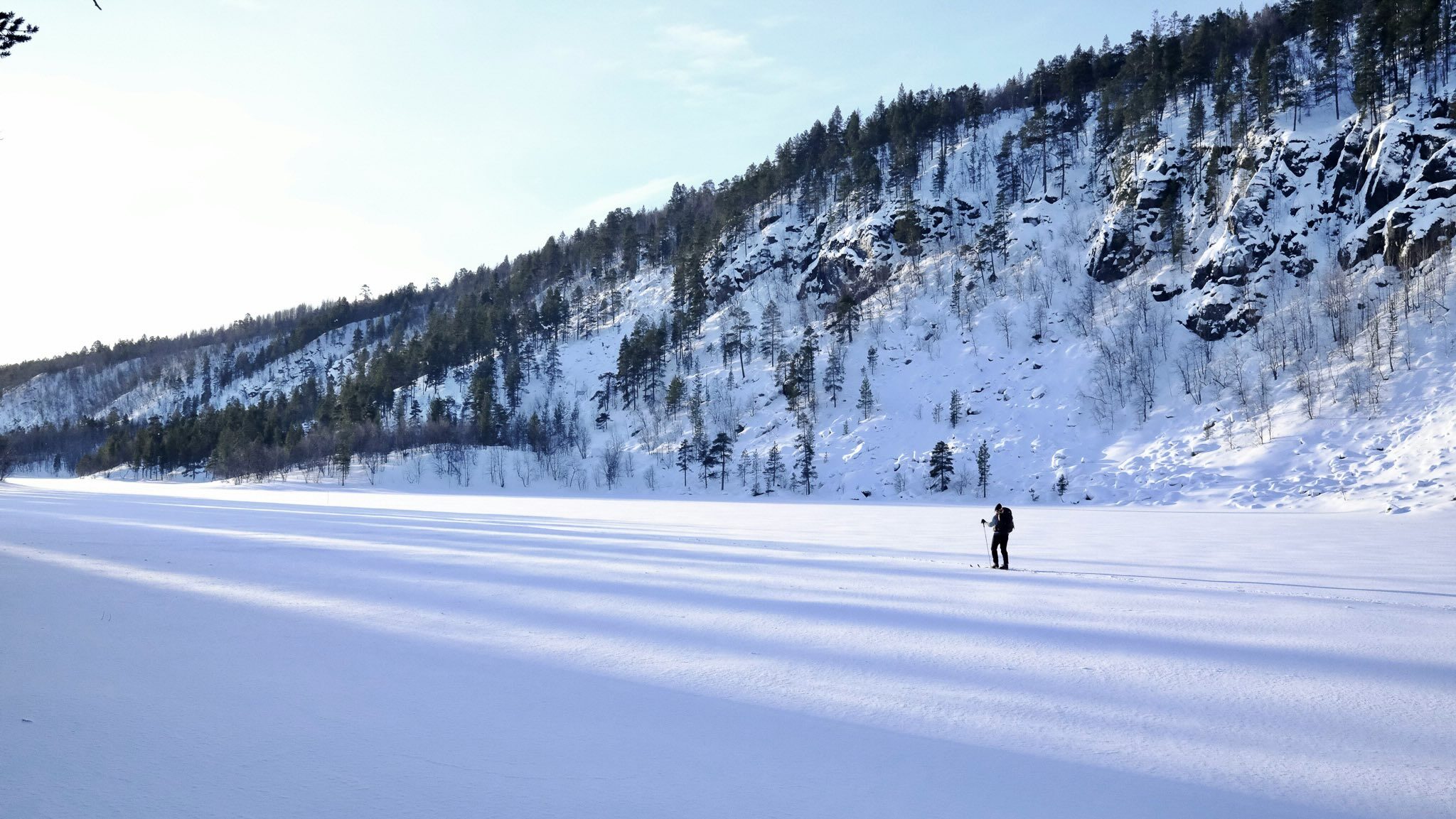 Woman walking on a snowy mountain trail in a winter alpine valley