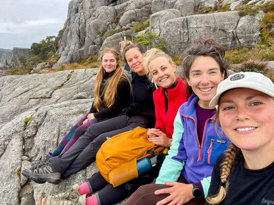 Women smiling on a rocky shoreline in Norway during a kayaking adventure holiday