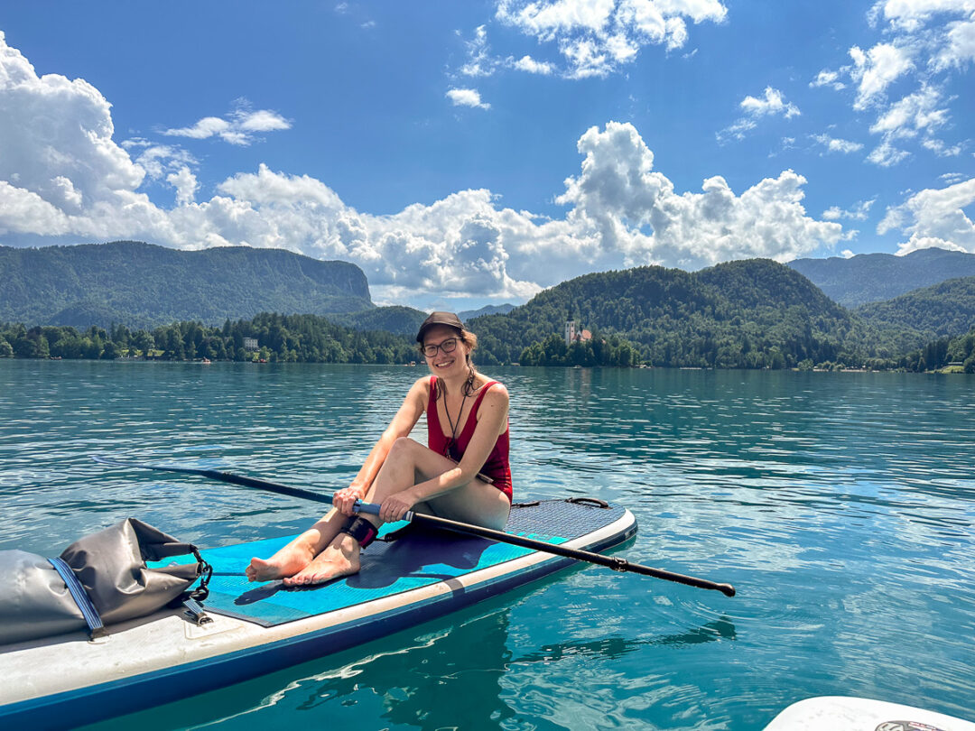 Women kayaking on a calm lake with forested mountains in the background