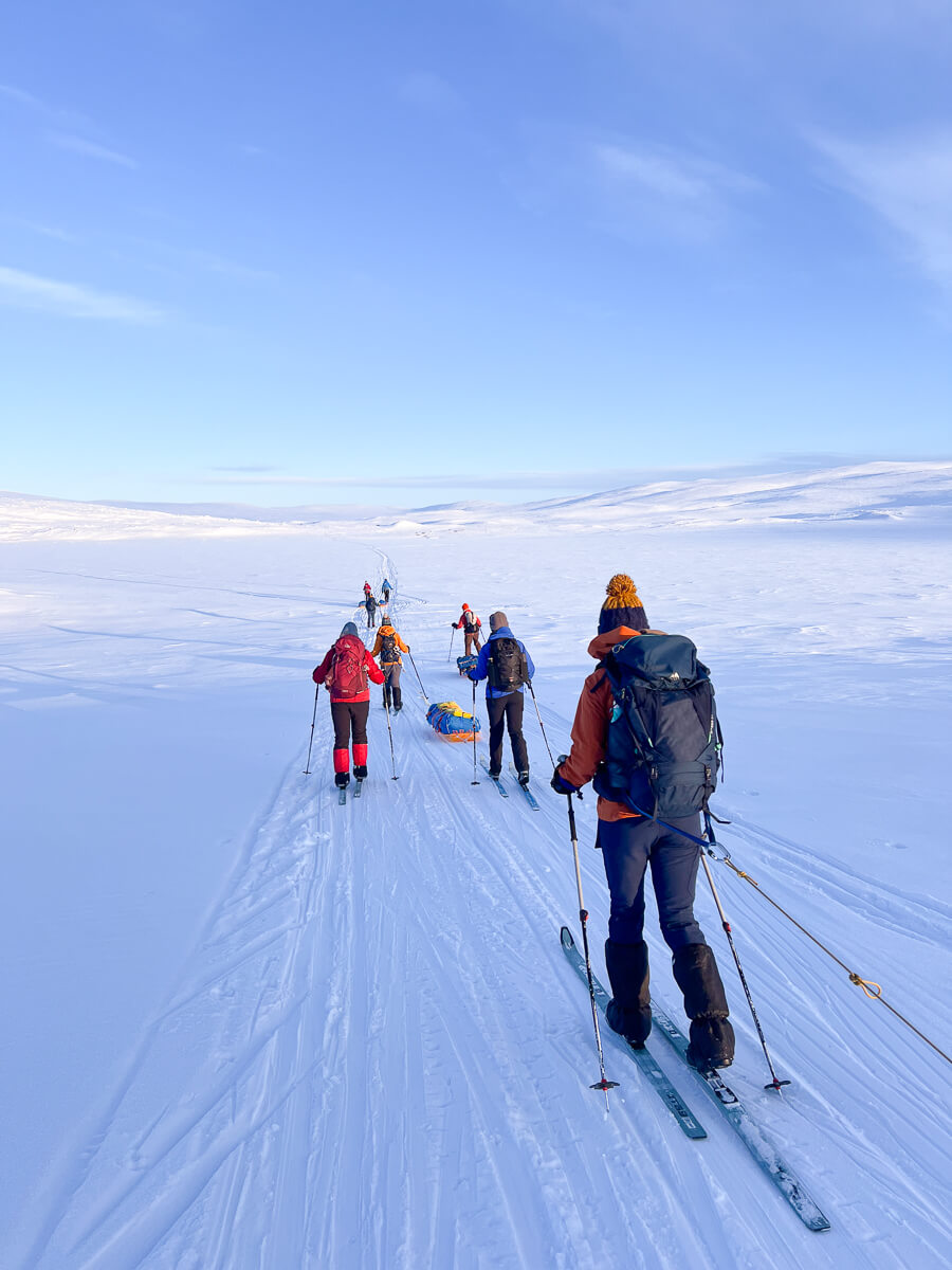 Women skiing on skis across snowy Arctic landscape during an arctic circle hut to hut ski expedition