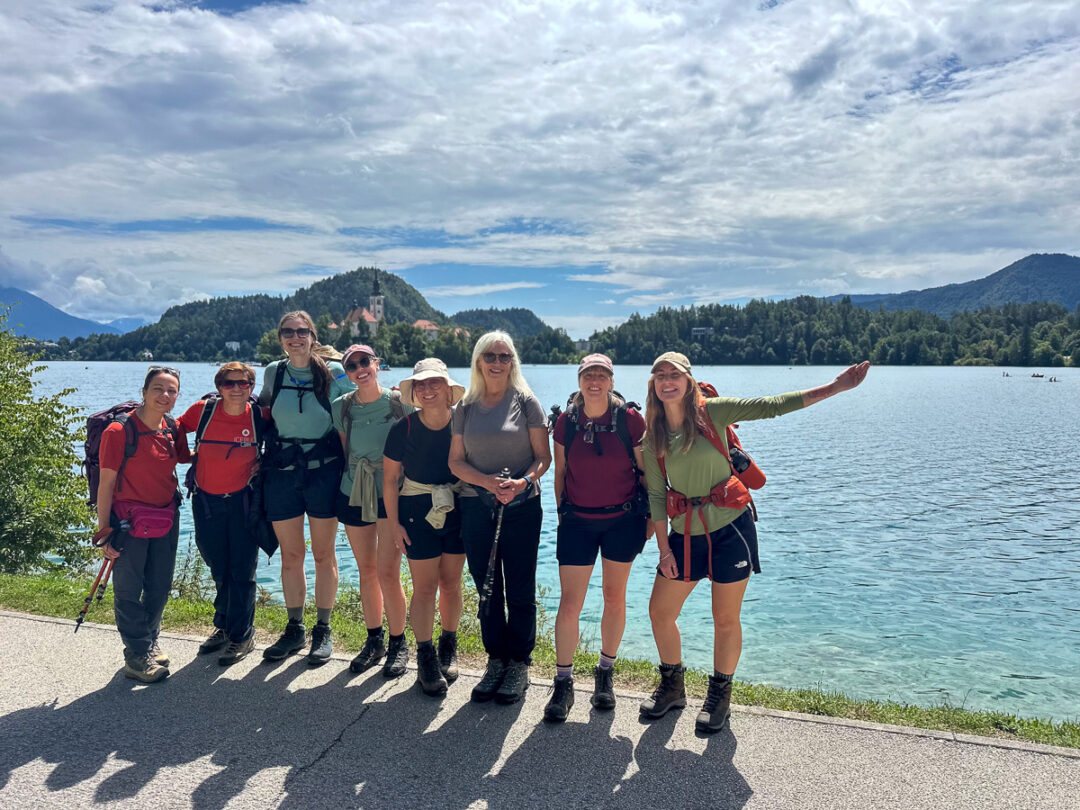 Women hikers posing by a lakeside in Slovenia during a hut-to-hut hiking adventure