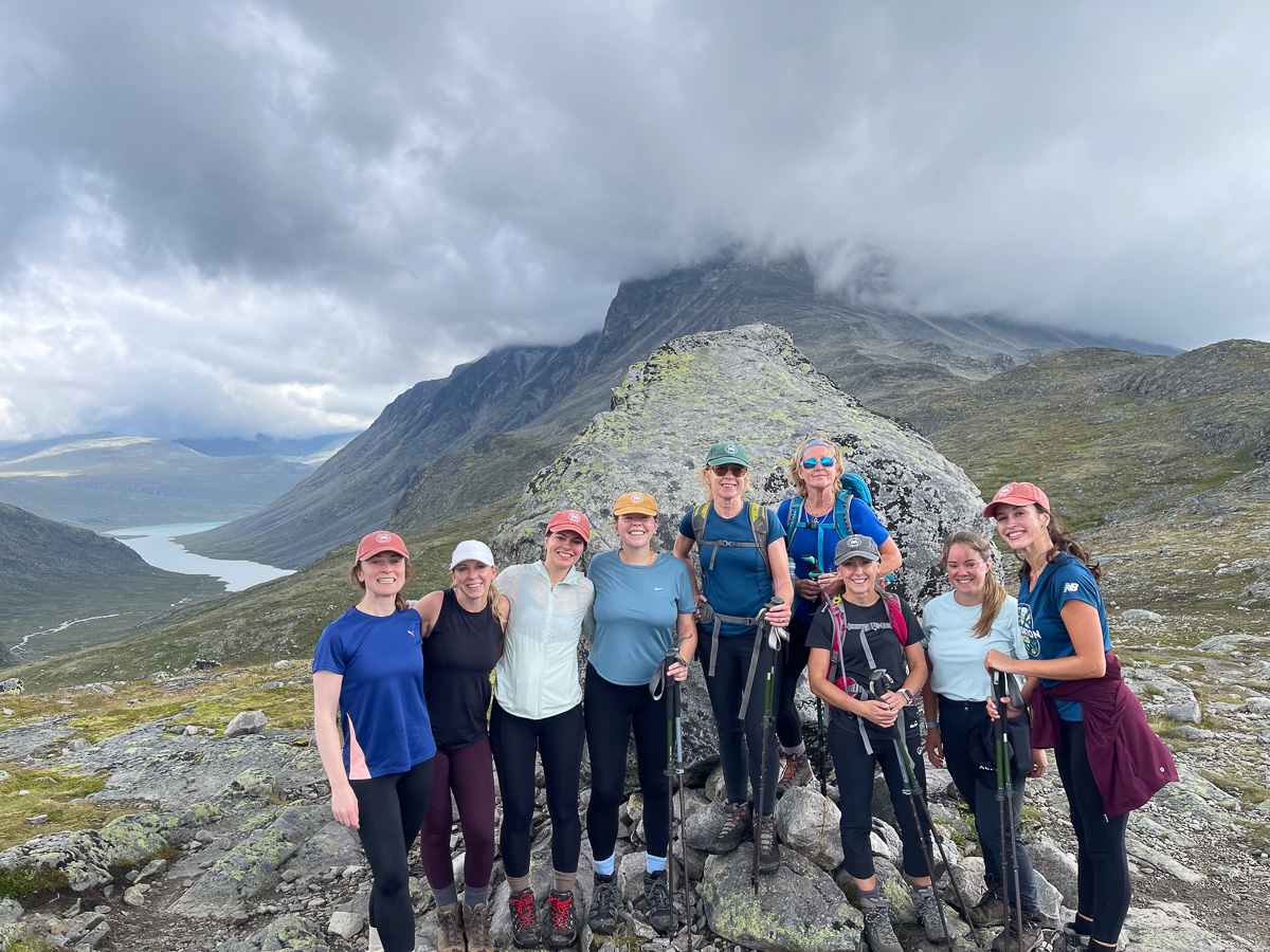 Women hiking on a mountain ridge in Norway with lakes and glaciers in the distance