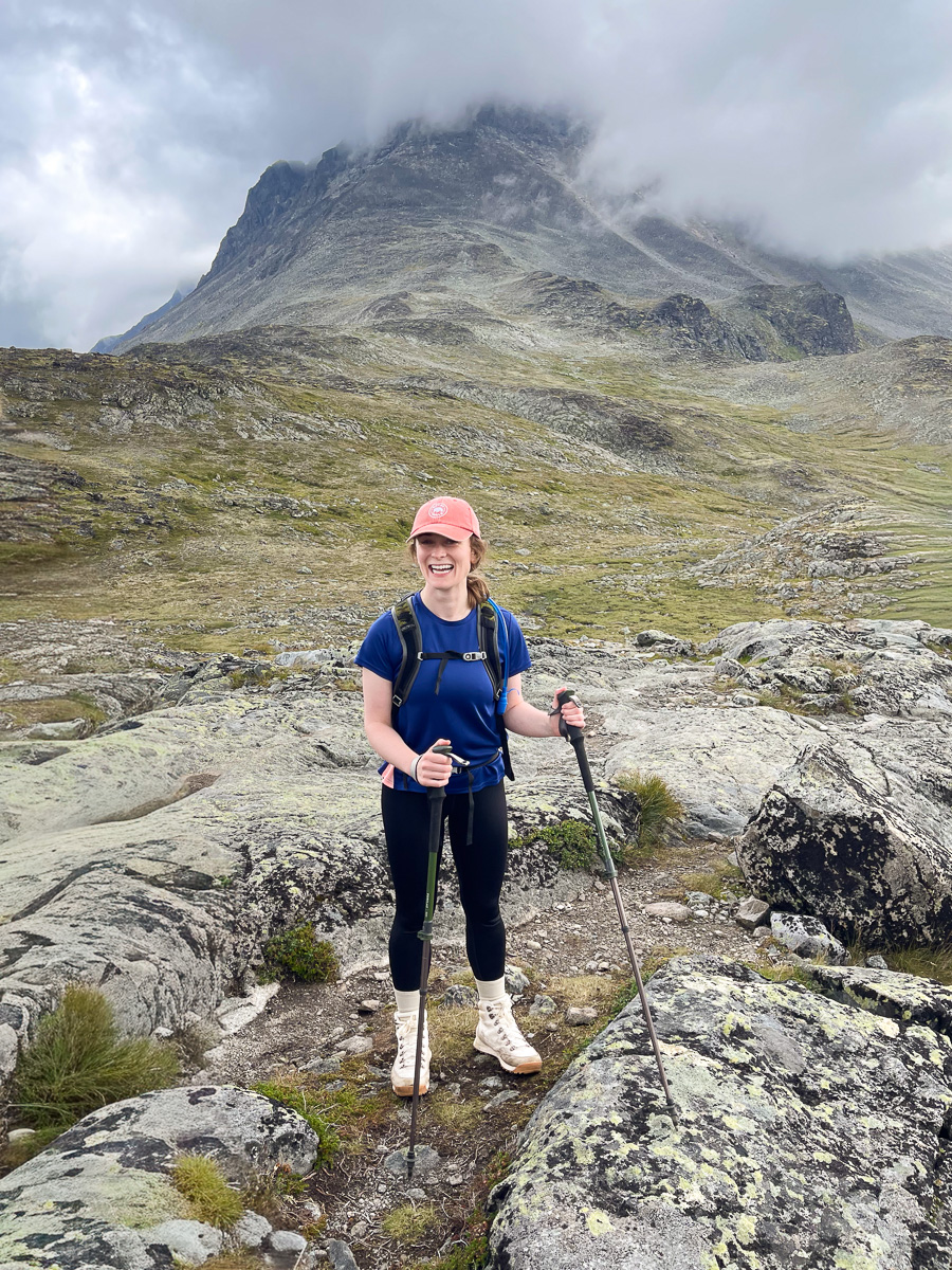 Woman hiking with trekking poles on rocky mountainside in Norway’s scenic highlands