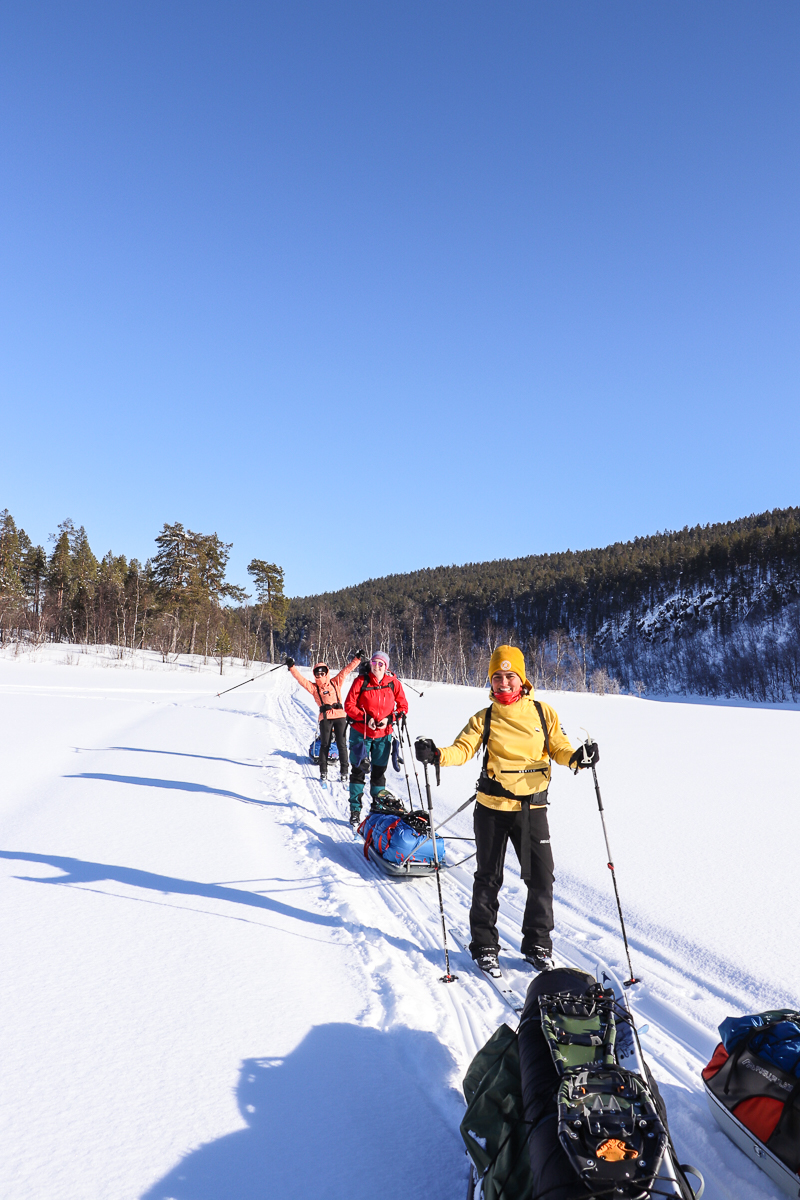 Women snow-skiing on a snowy trail with poles, winter forest hills in the Arctic ski expedition landscape