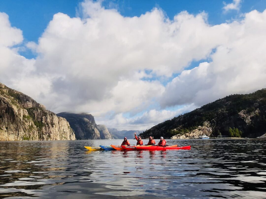 Women kayaking on a fjord under dramatic mountain cliffs