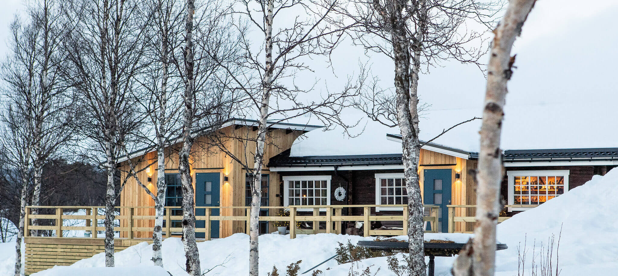 Snowy Swedish landscape with wooden cabins and birch trees outside a winter retreat