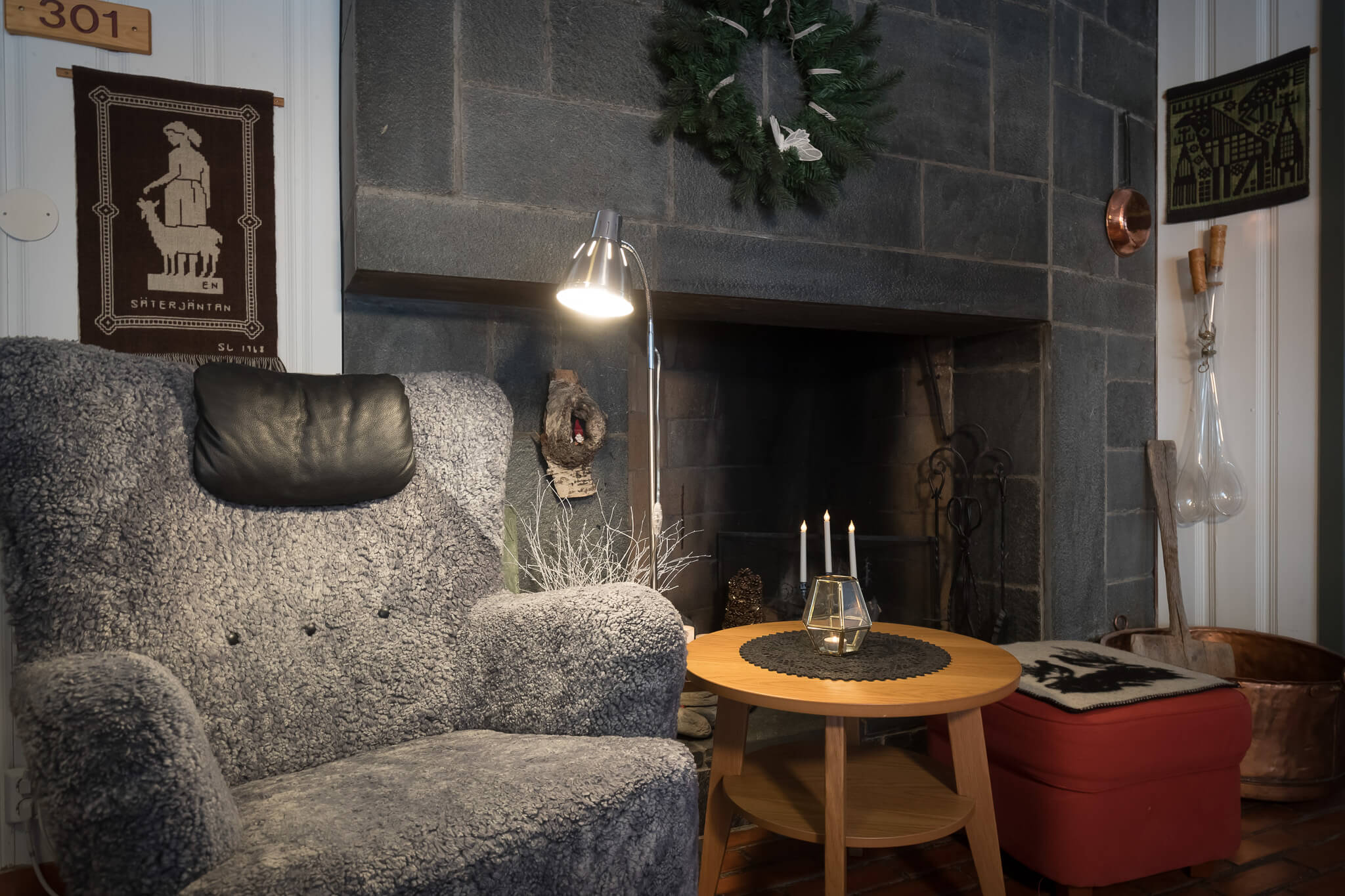 Cozy living room corner with a stone fireplace, armchair, and candles on a small side table