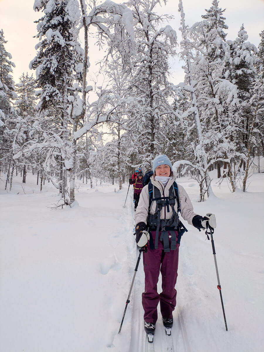 Woman cross-country skiing through snowy pine trees in a winter landscape