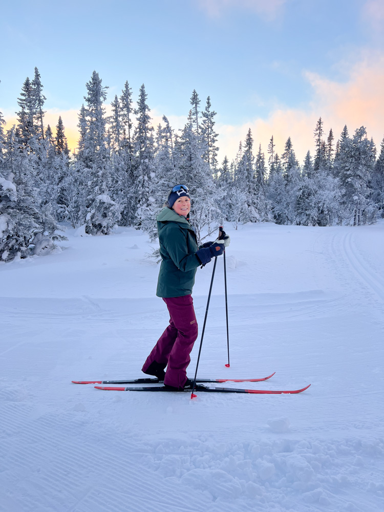 Woman skiing on a groomed slope in snowy Swedish forest at dusk