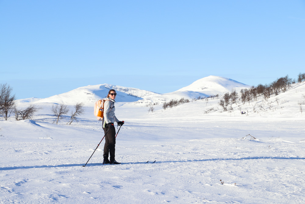 Woman skiing on snowy Swedish mountains under a clear blue sky, beginner-friendly winter conditions