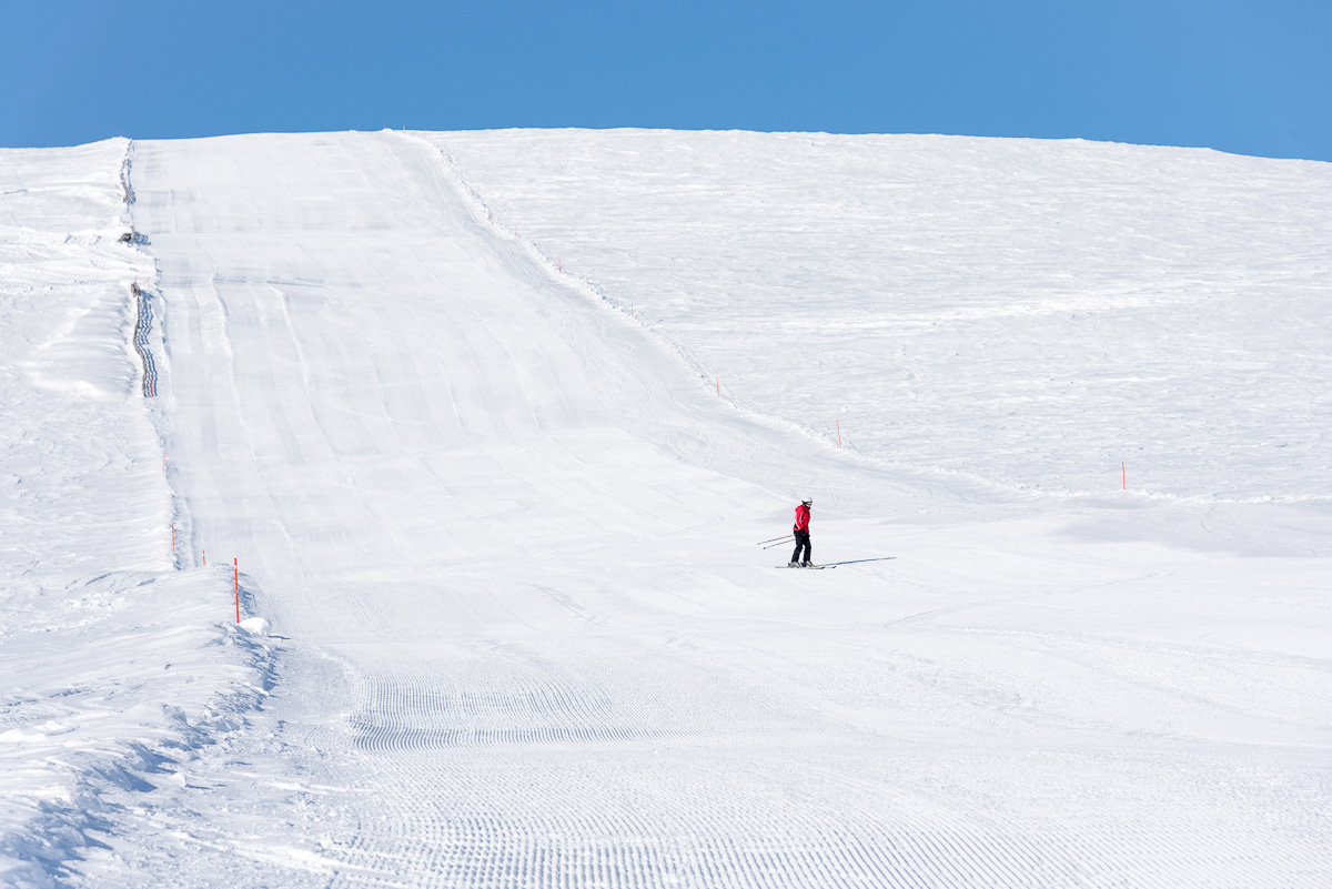 Woman skiing downhill on a groomed slope in Sweden, beginner-friendly pistes.