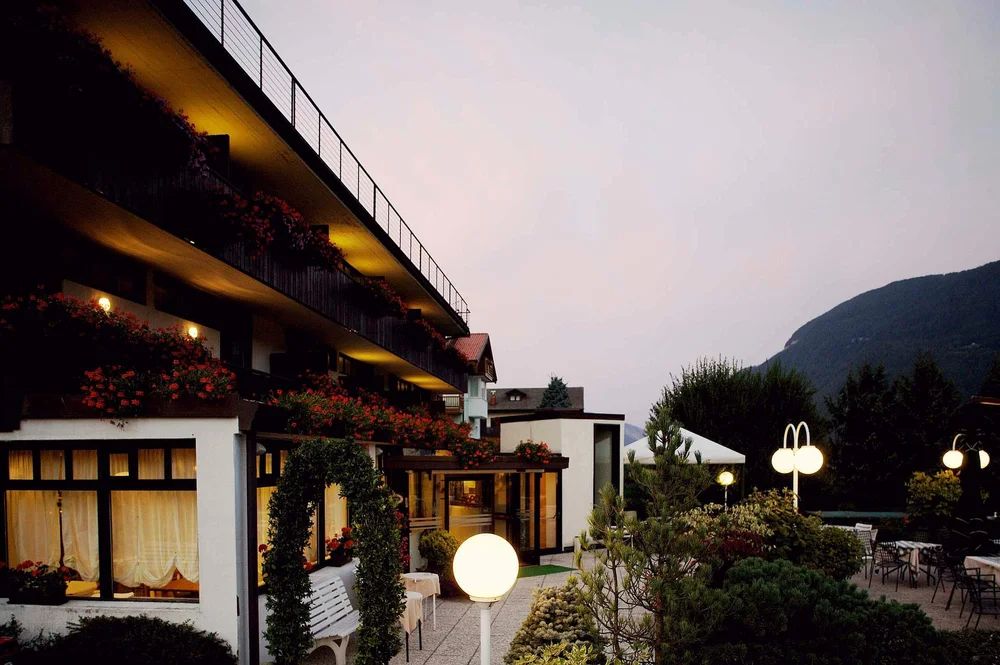 Mountain hotel terrace at dusk with warm lights and flowered balconies