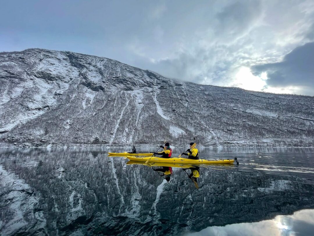 women kayakers on calm, reflective water in Norway