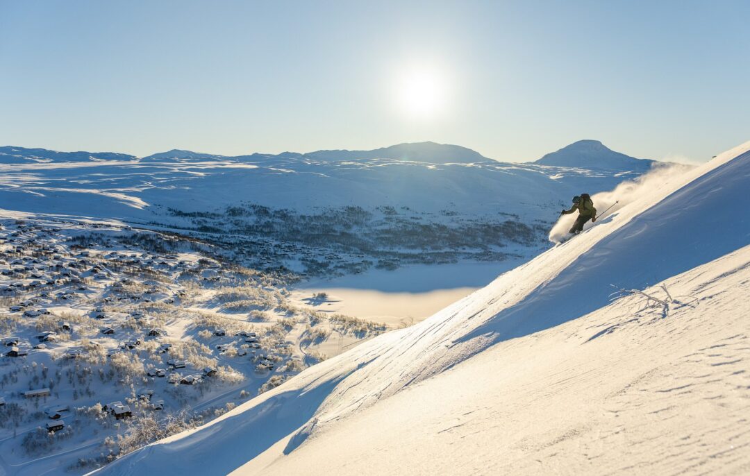 Skier descending a snow-covered mountain slope in a winter alpine valley
