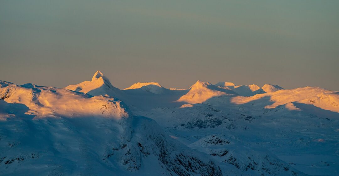 Snow-covered mountain peaks over a winter landscape in Norway at dusk