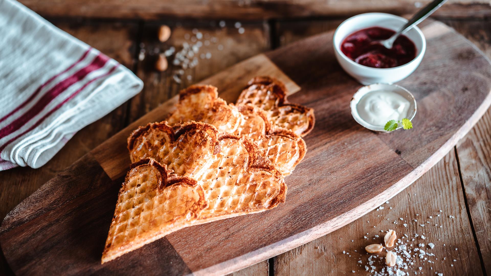 Freshly baked bread on a wooden table with jam and cream dips in bowls