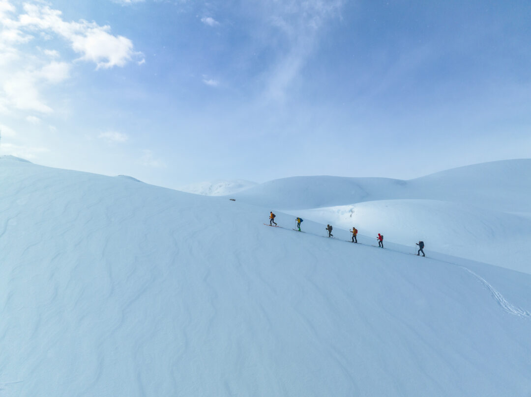 Women ski touring across snowy Norwegian mountains under a clear blue sky