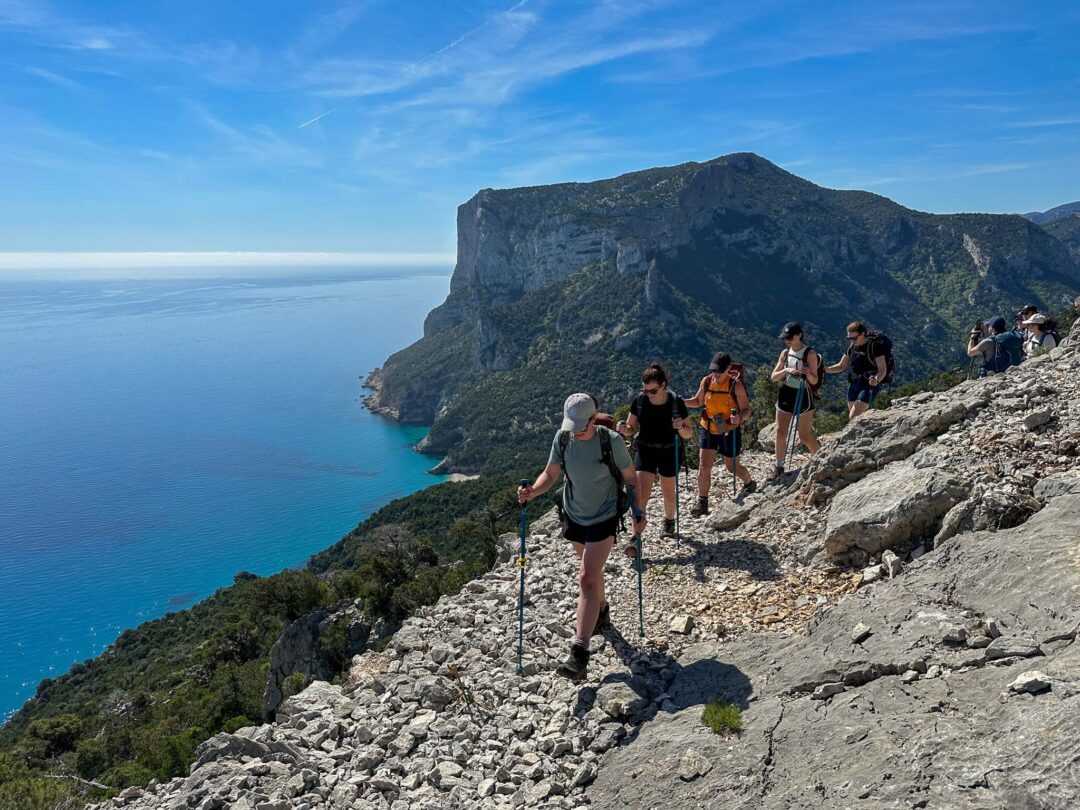 Women hiking along a rocky coastal trail on Sardinia’s east coast with cliff and sea views