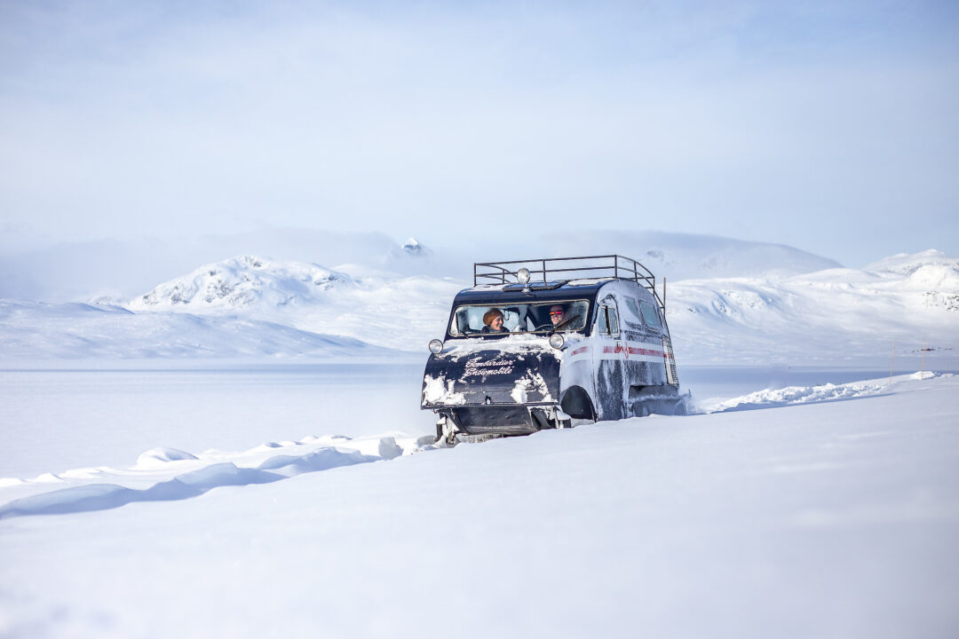 Off-road van driving through a snow-covered mountain landscape in winter conditions