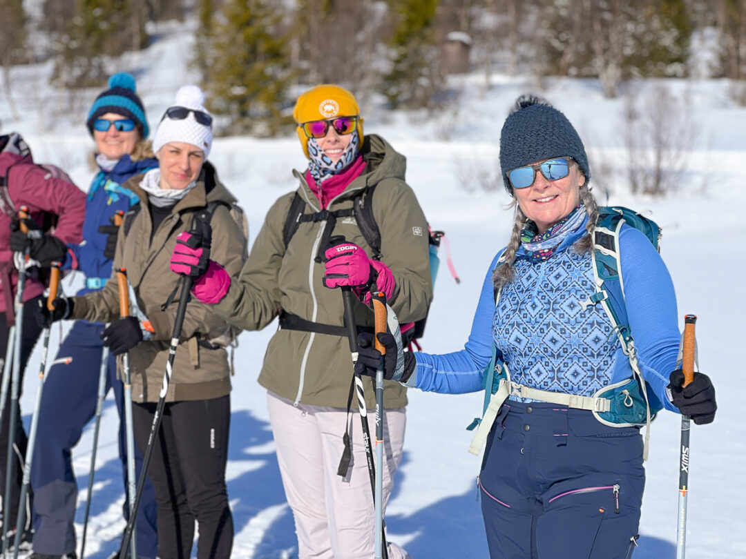 Women cross-country skiing on a snowy track in a winter forest, wearing helmets, skis and poles